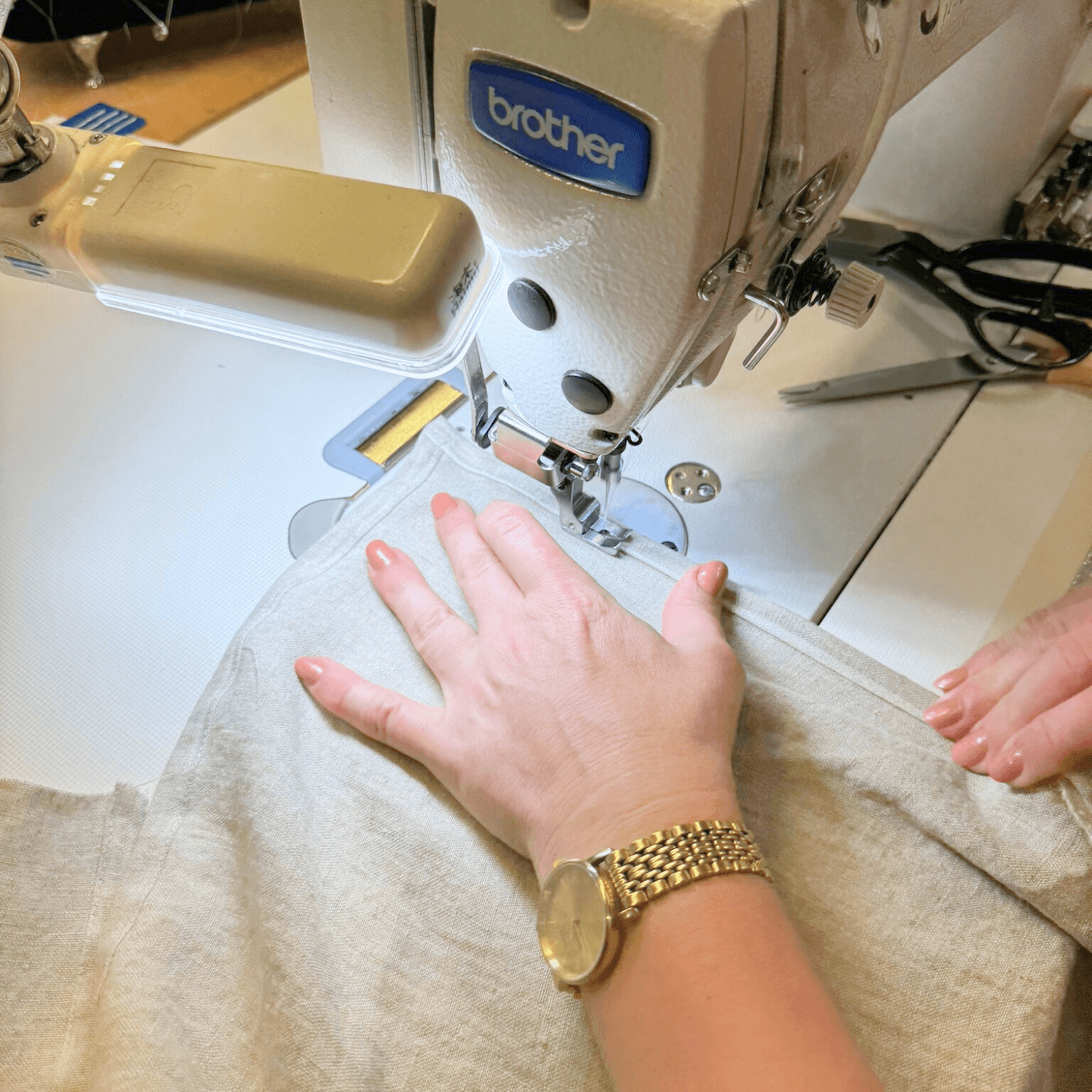 Hands sewing linen fabric in a small textile workshop