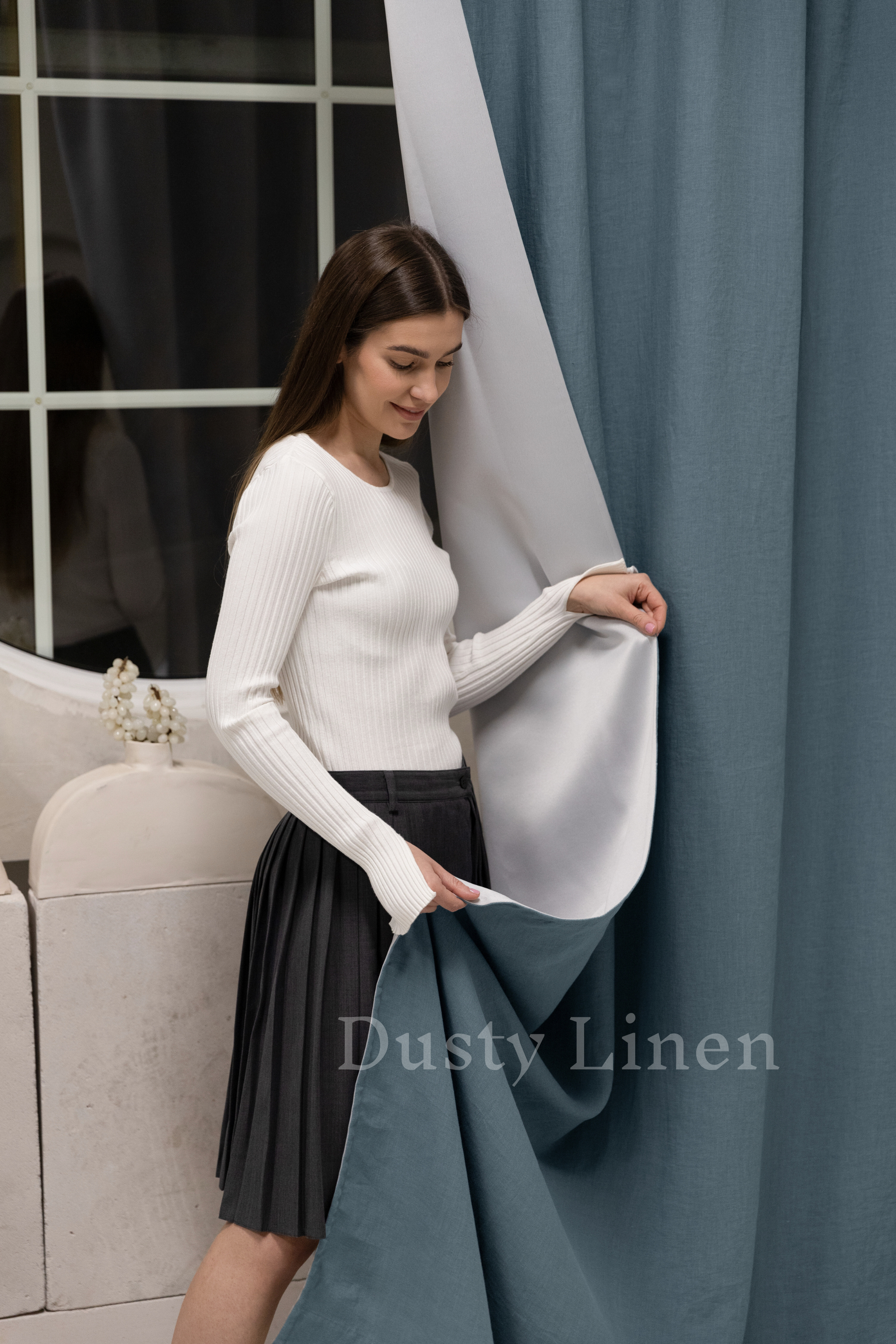 a woman standing next to a curtain in front of a window