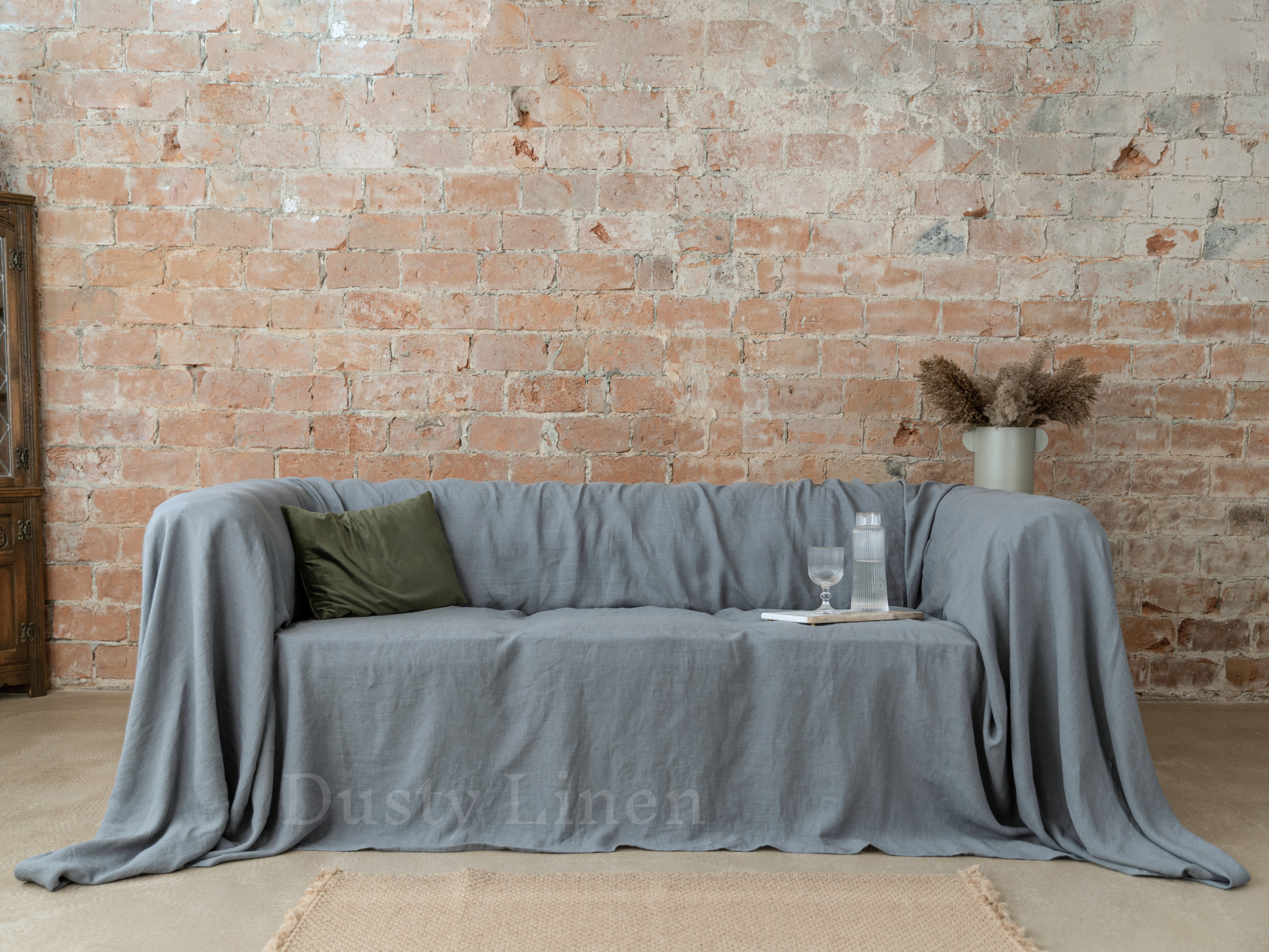a couch covered with a blanket next to a brick wall