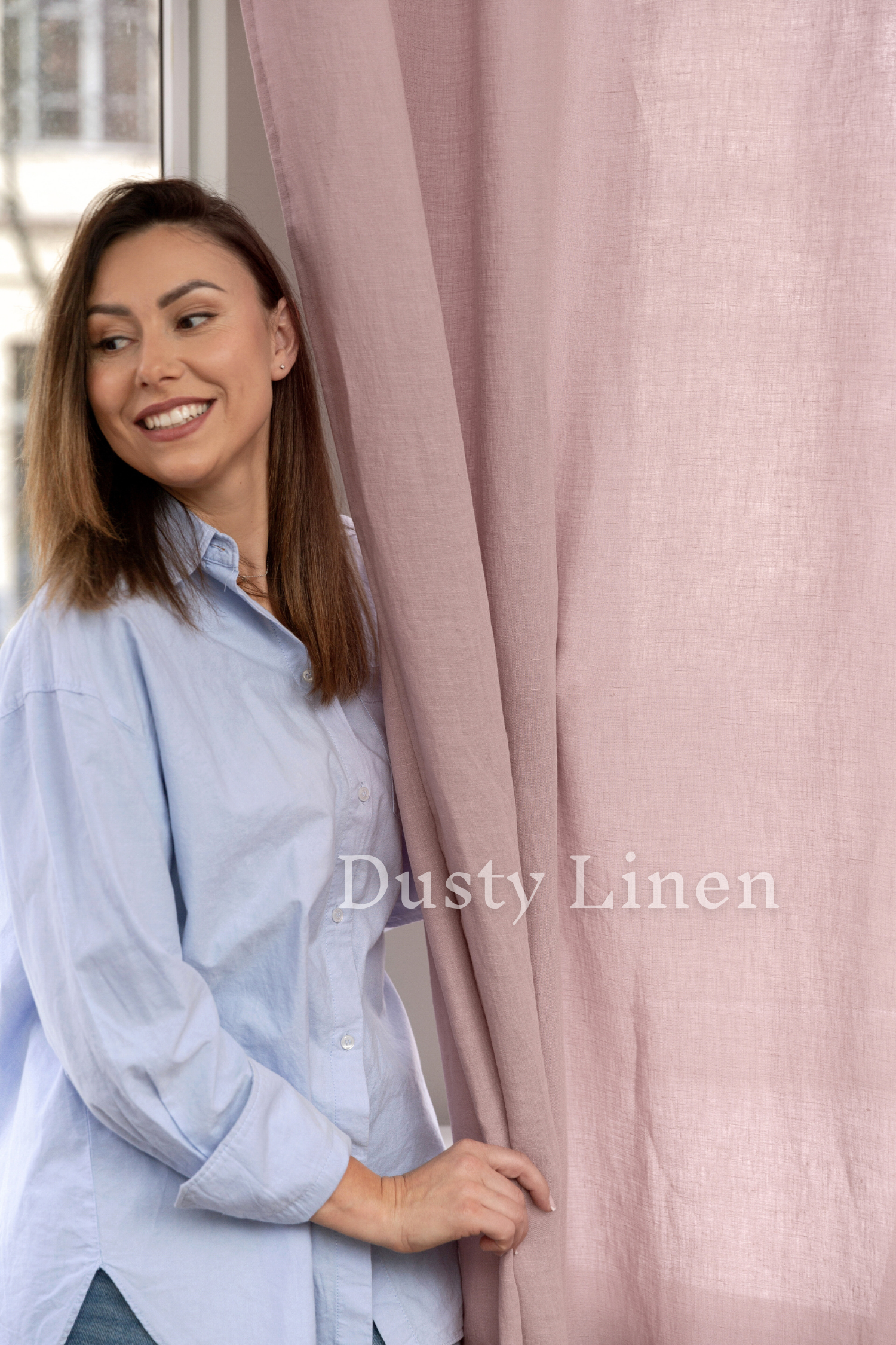 a woman standing next to a pink curtain