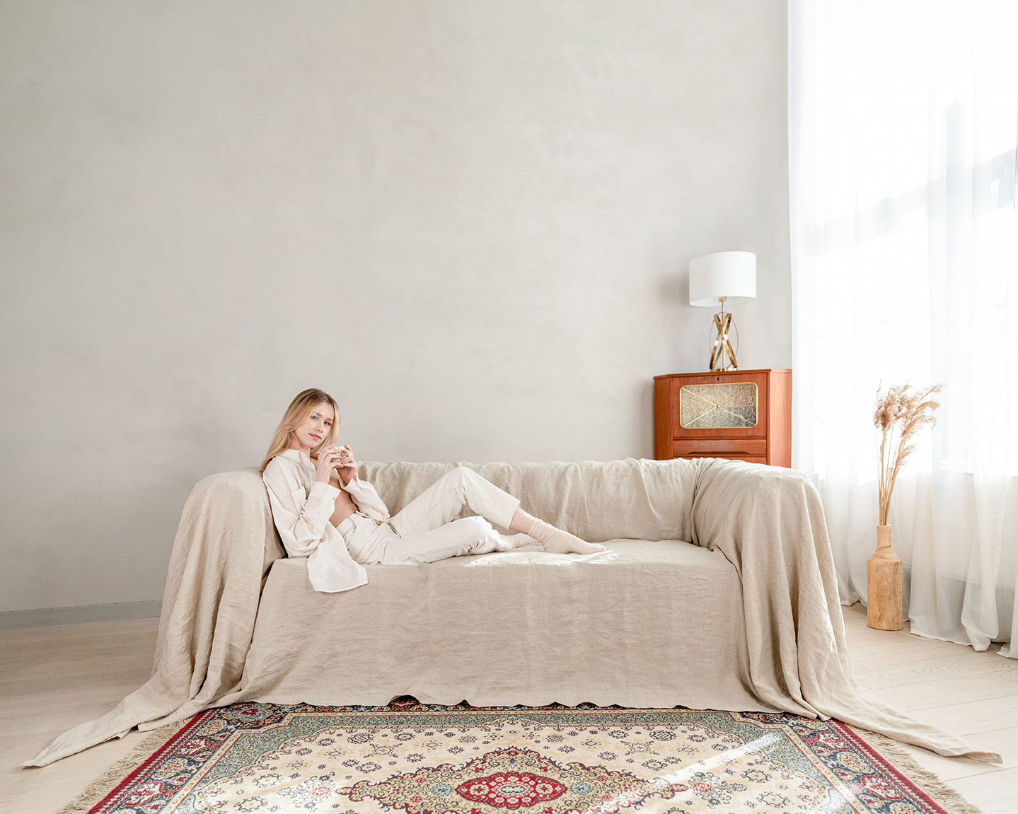 a woman sitting on a couch in a natural linen couch cover in a living room