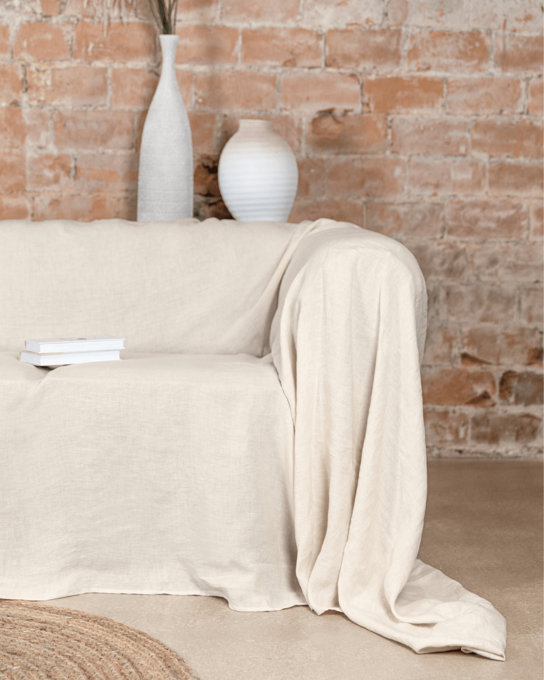 a couch covered with a white blanket next to a brick wall