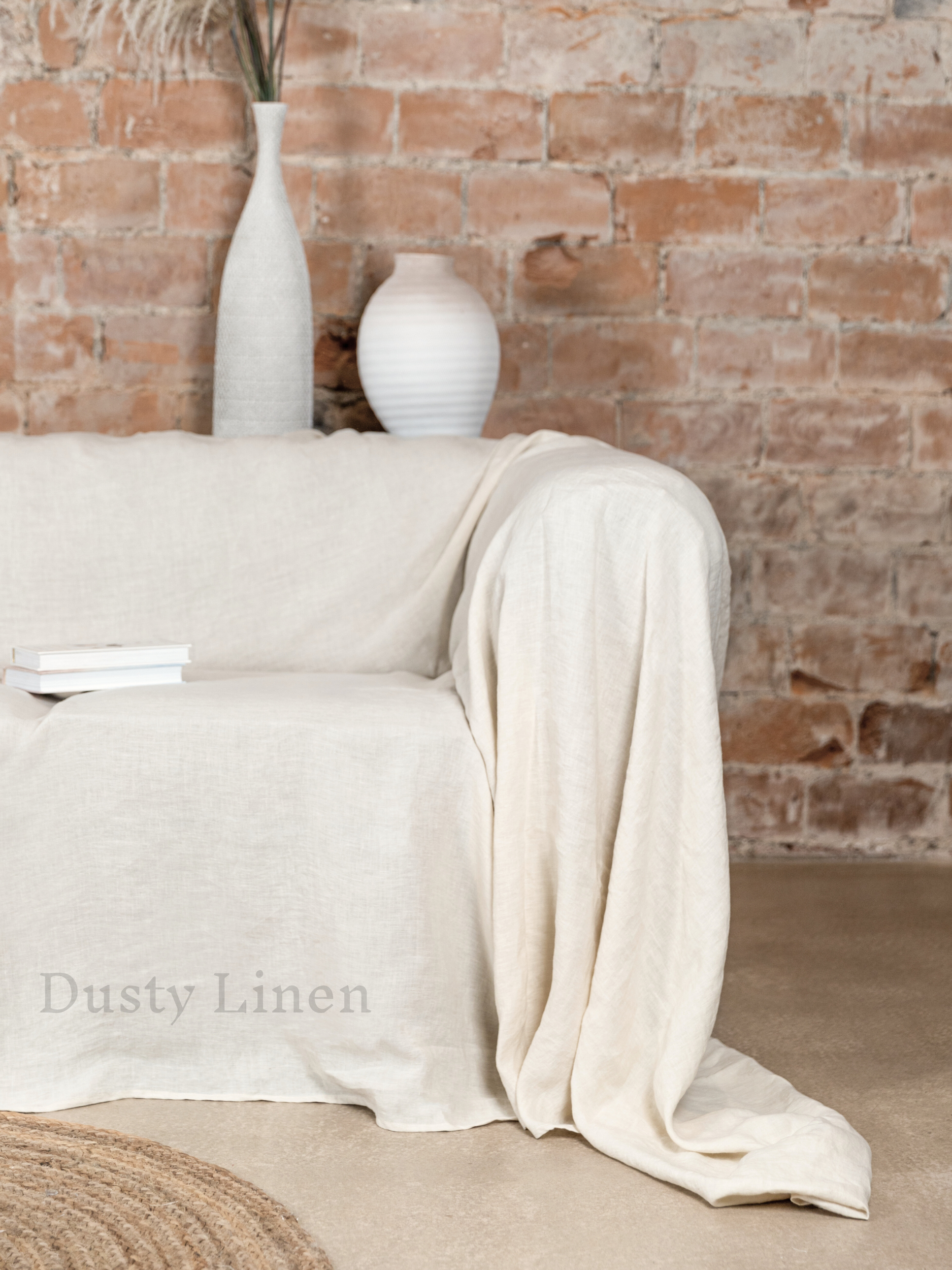 a couch covered with a white blanket next to a brick wall