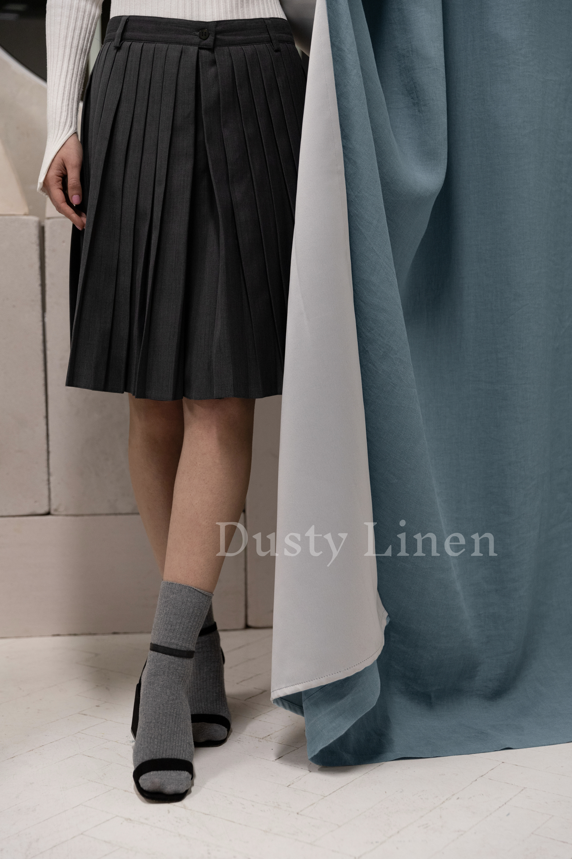 a woman standing next to a curtain wearing a skirt