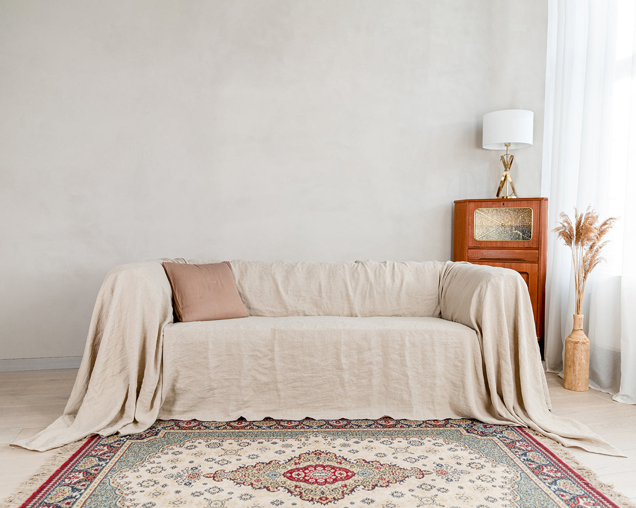 a living room with a couch covered in a natural linen couch cover