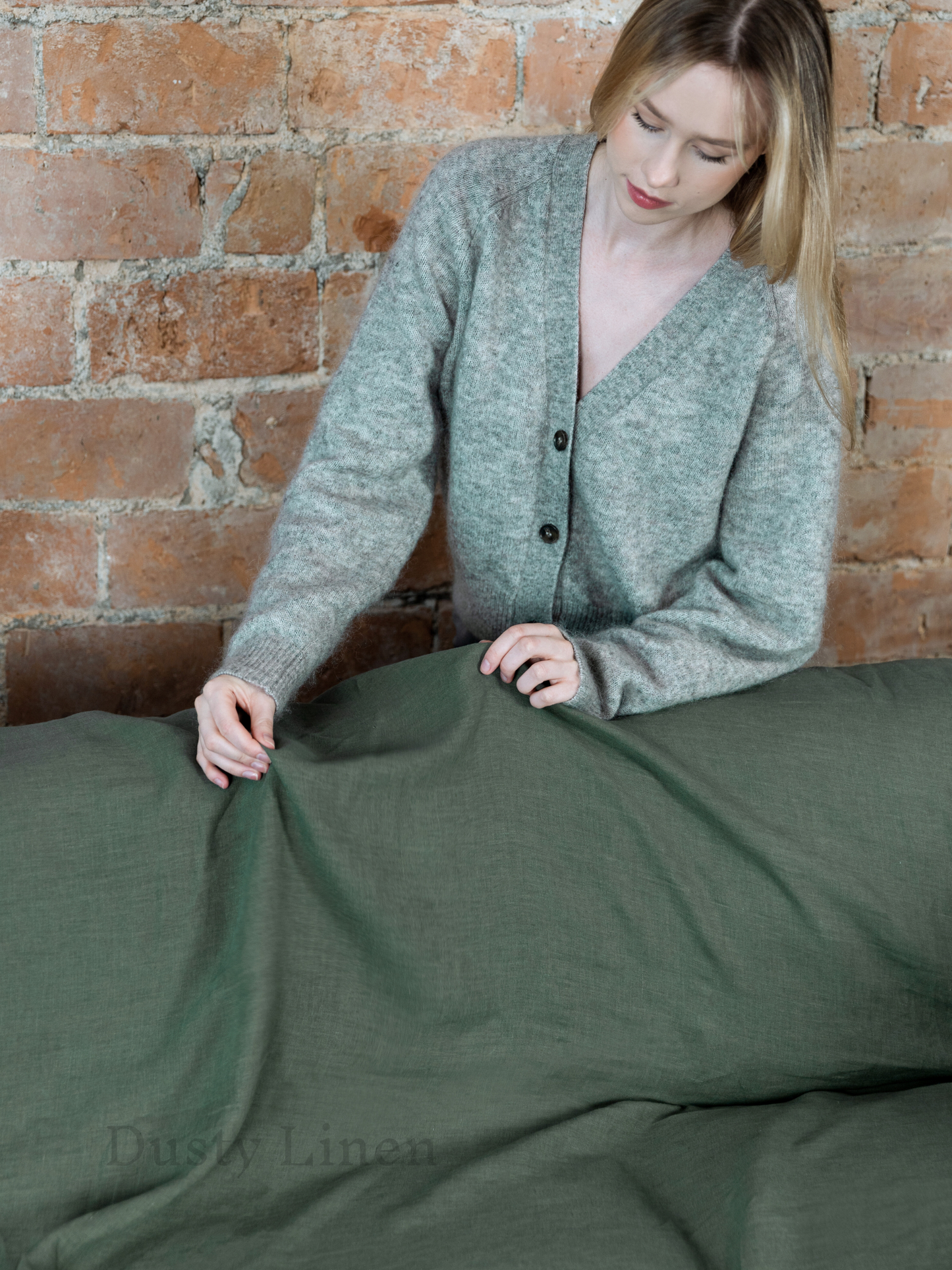 a woman in a gray cardigan laying on a bed