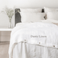 a bed with a white comforter and pillows