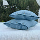 a pair of blue pillows sitting on top of a bed