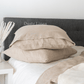 a bed topped with pillows and blankets next to a night stand