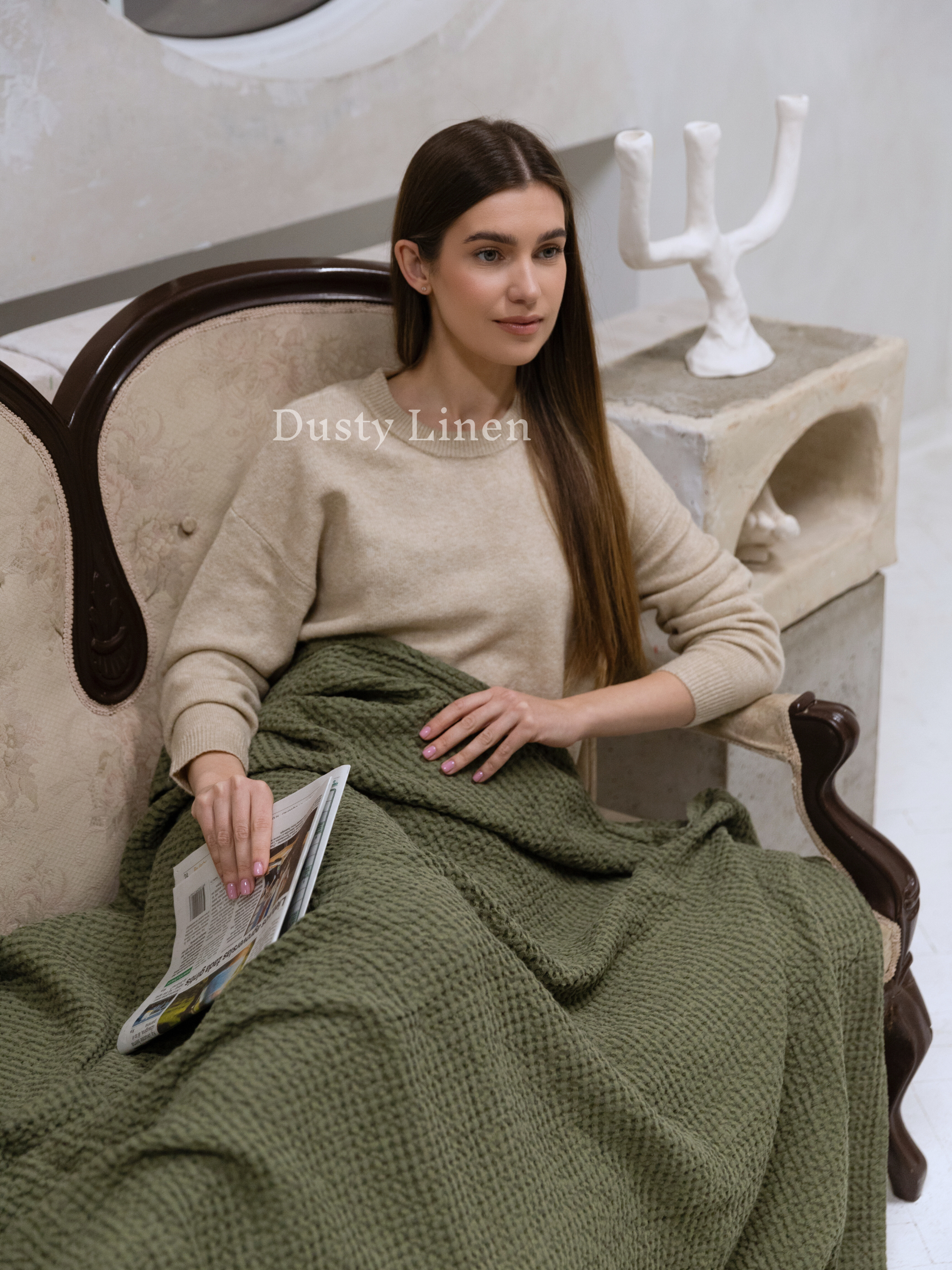 a woman sitting in a chair with a green blanket