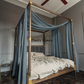 a four poster bed with blue drapes and a ceiling fan