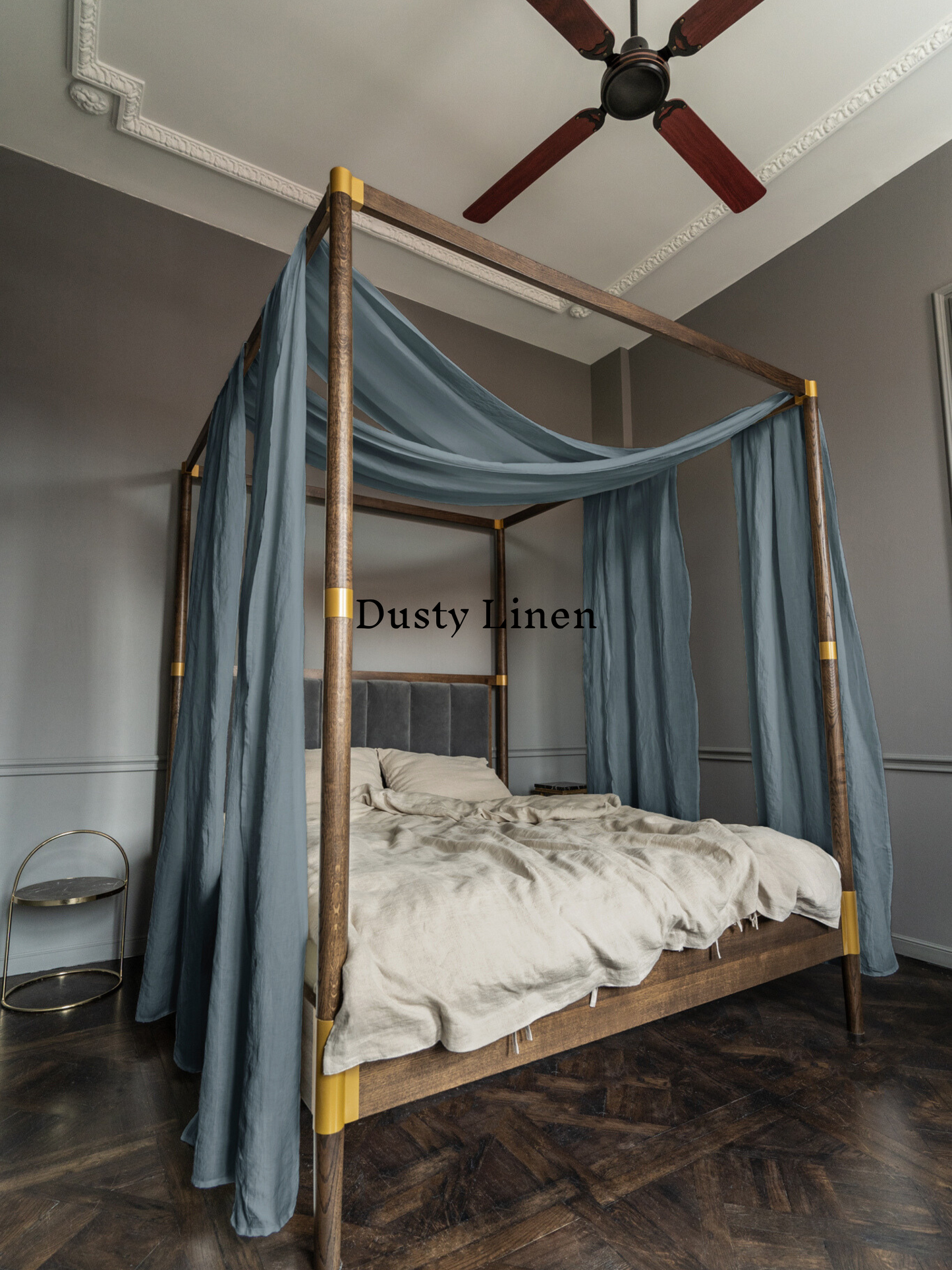 a four poster bed with blue drapes and a ceiling fan