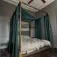 a four poster bed with green drapes and a ceiling fan