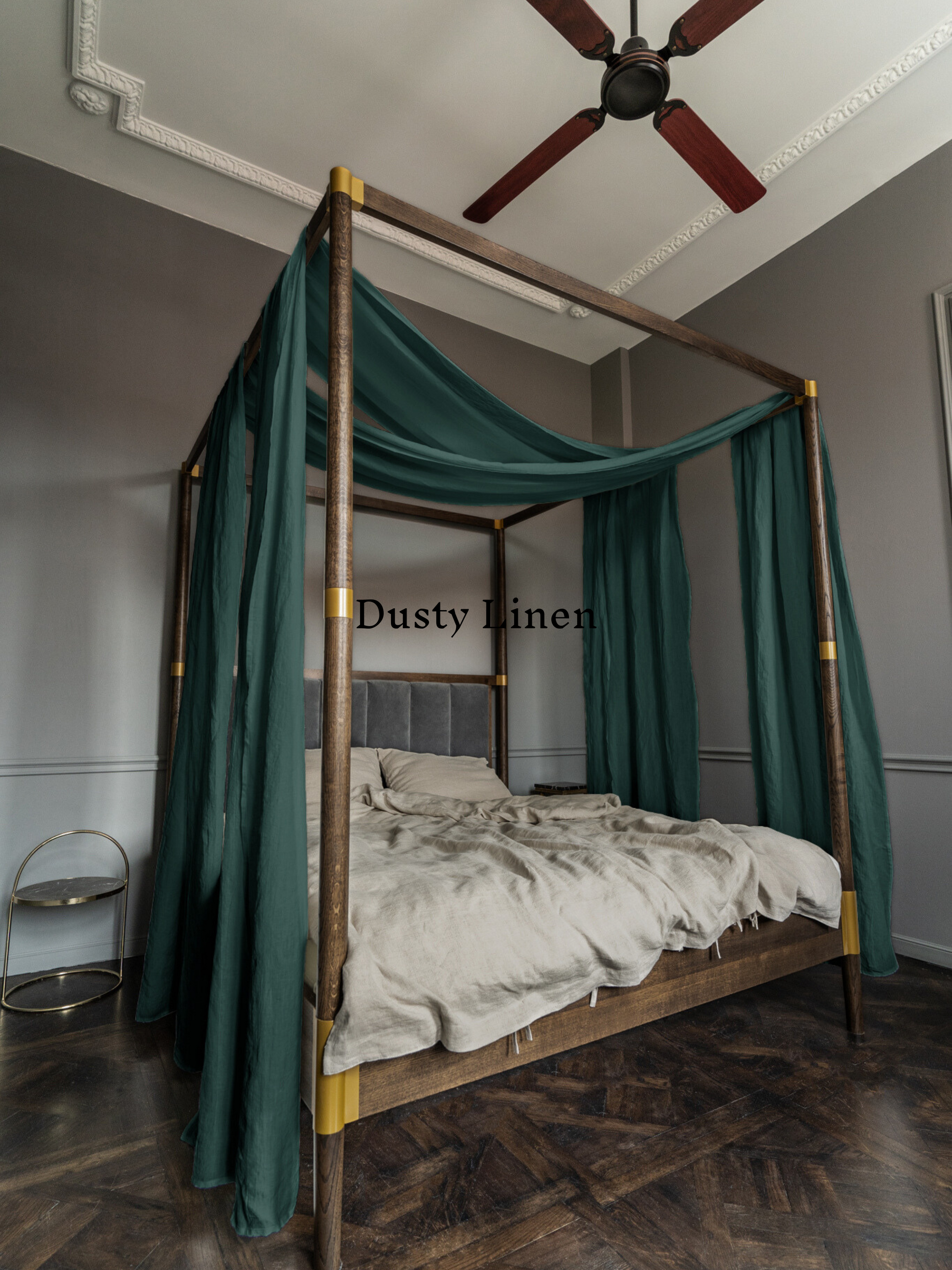 a four poster bed with green drapes and a ceiling fan