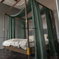 a four poster bed with green drapes on it