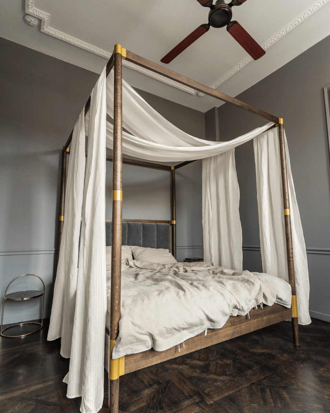 a four poster bed with white drapes and a ceiling fan