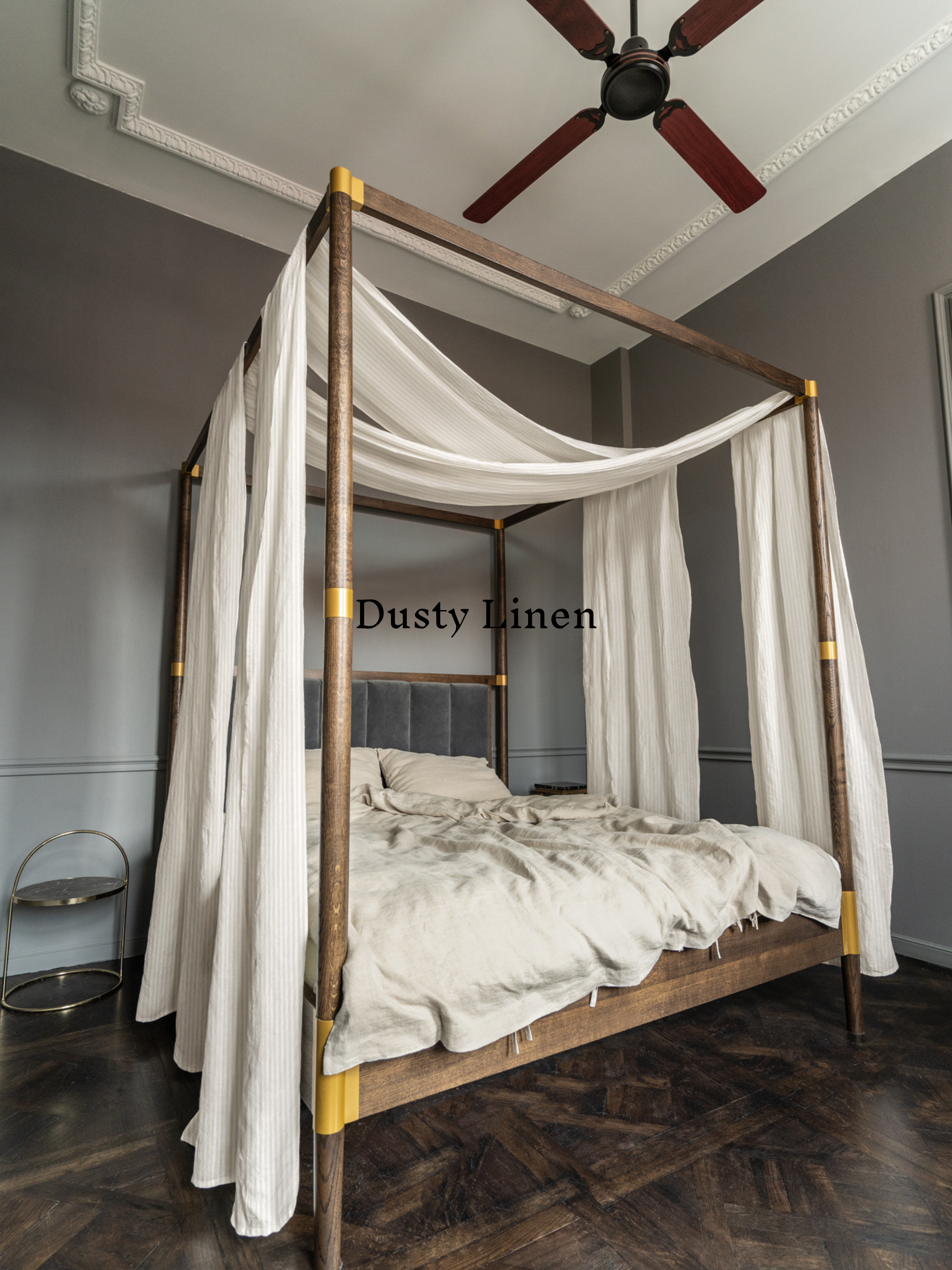 a four poster bed with white drapes and a ceiling fan