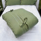 a white bed with a green pillow on top of it