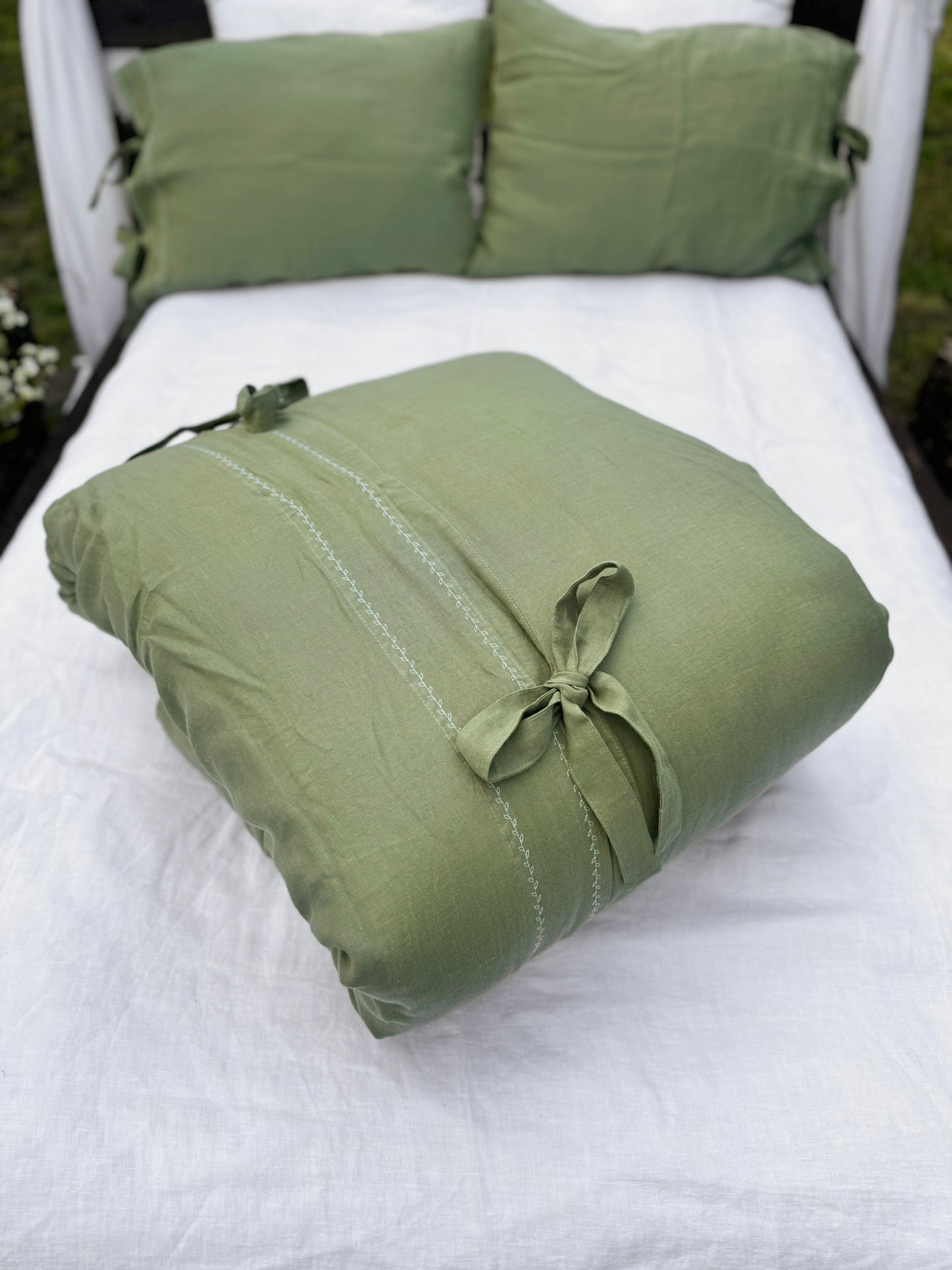 a white bed with a green pillow on top of it