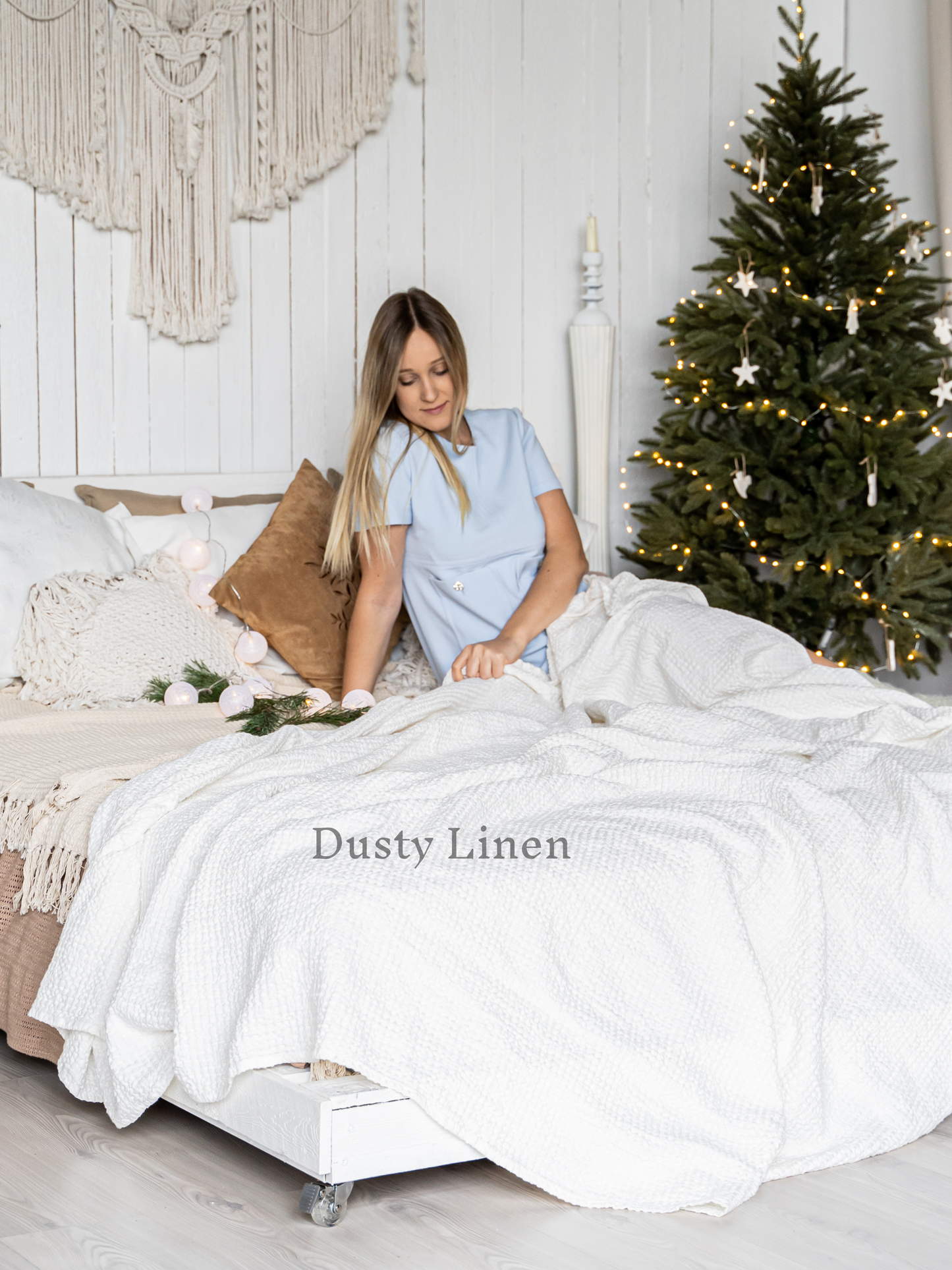 a woman sitting on a bed in front of a christmas tree