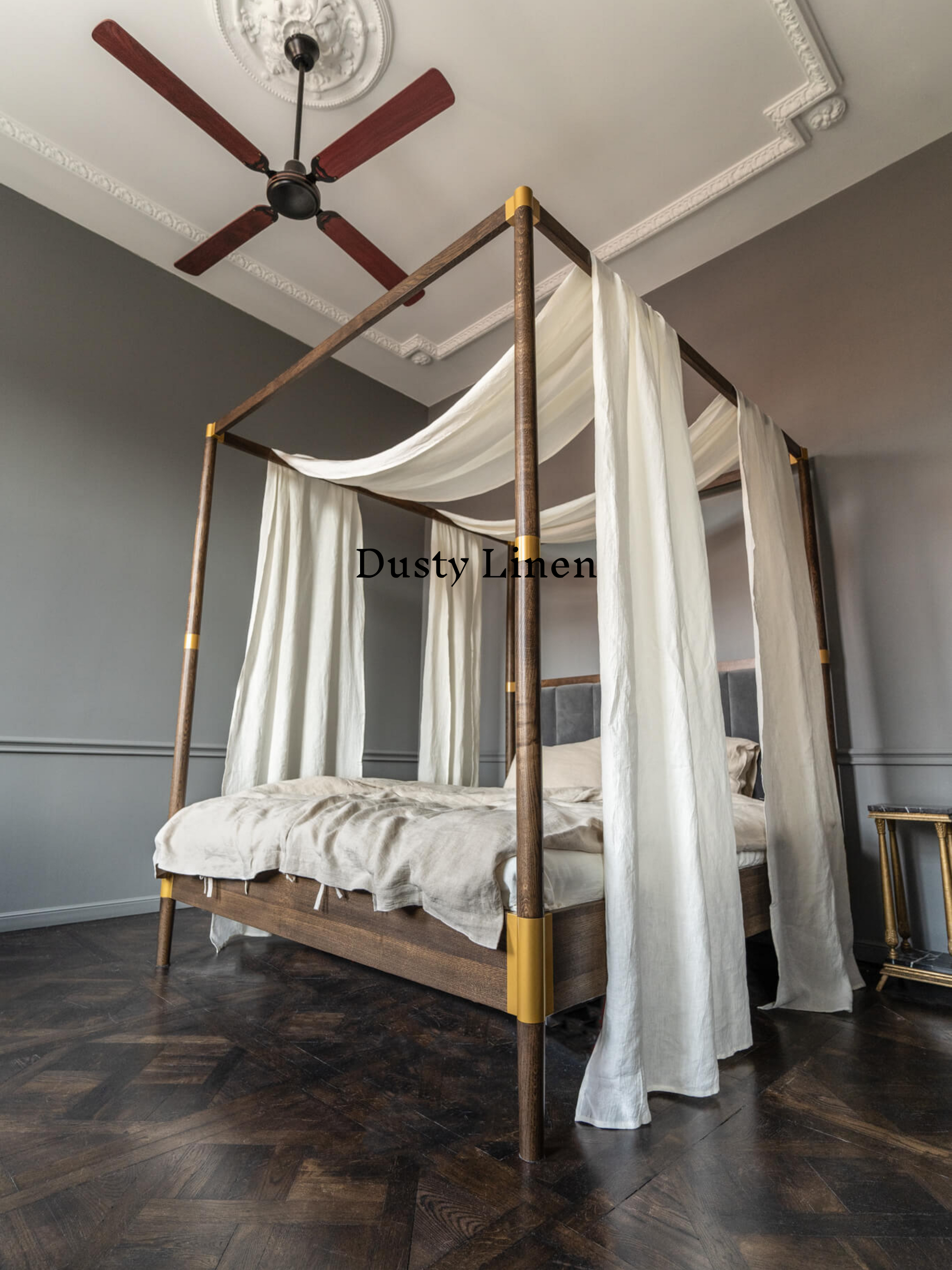 a canopy bed with white drapes and a ceiling fan