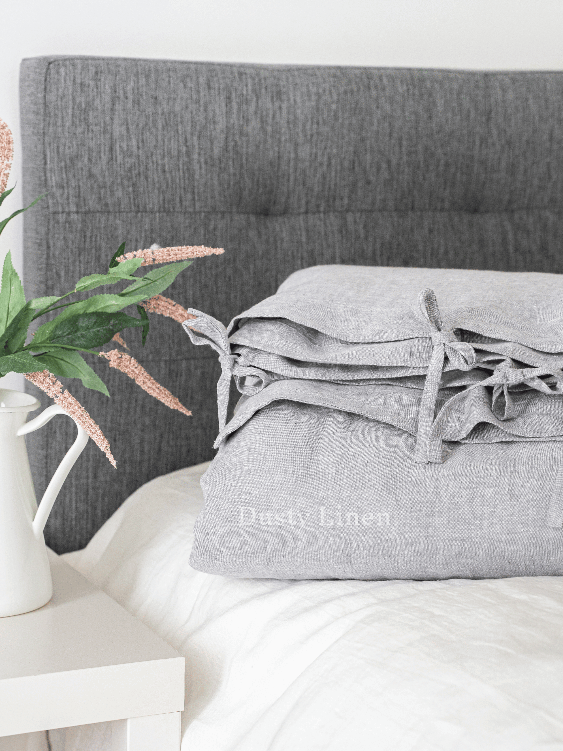 a bed with a gray headboard and pillows