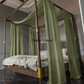 a canopy bed with a green drape over it