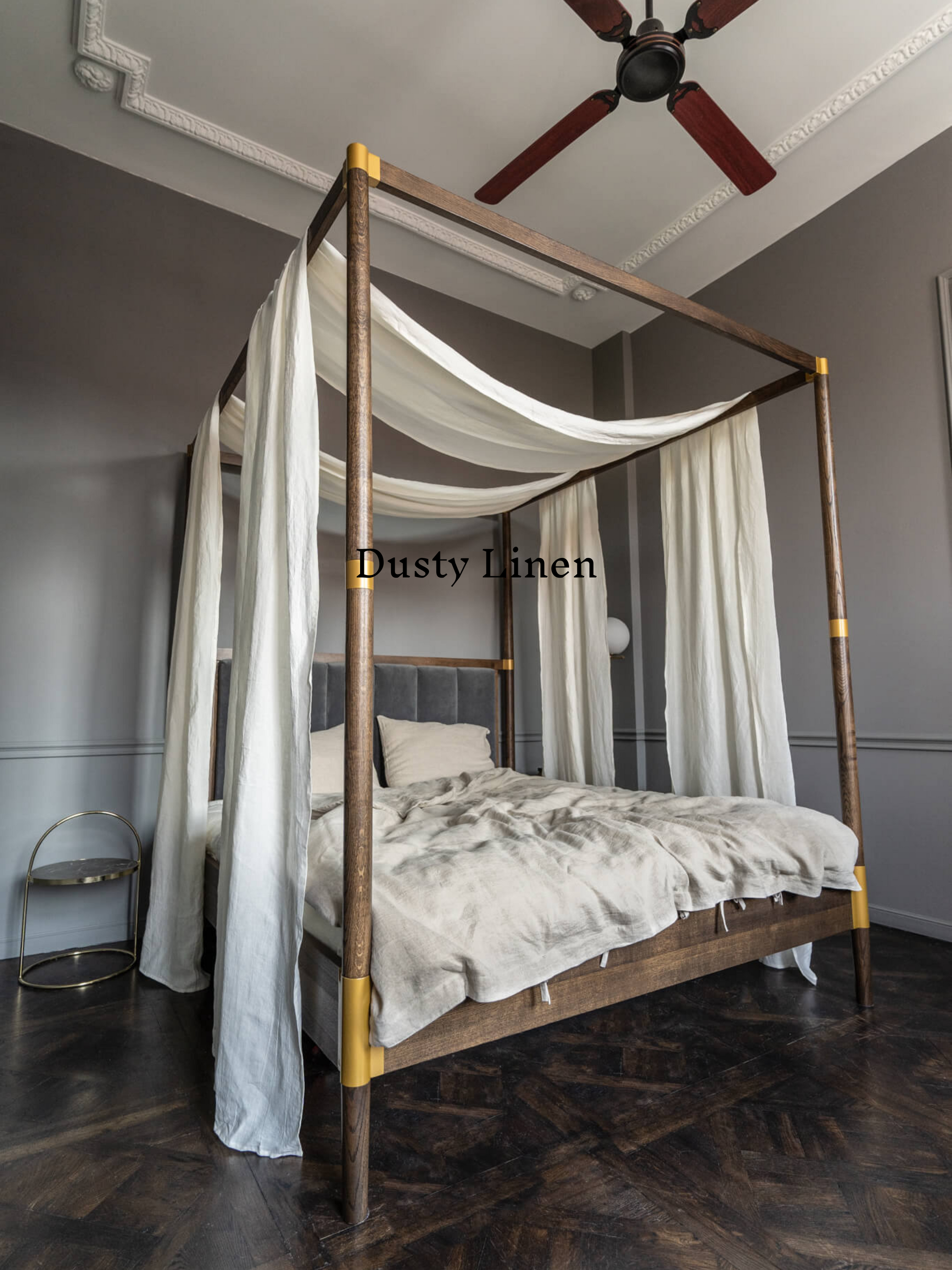 a four poster bed with white drapes and a ceiling fan