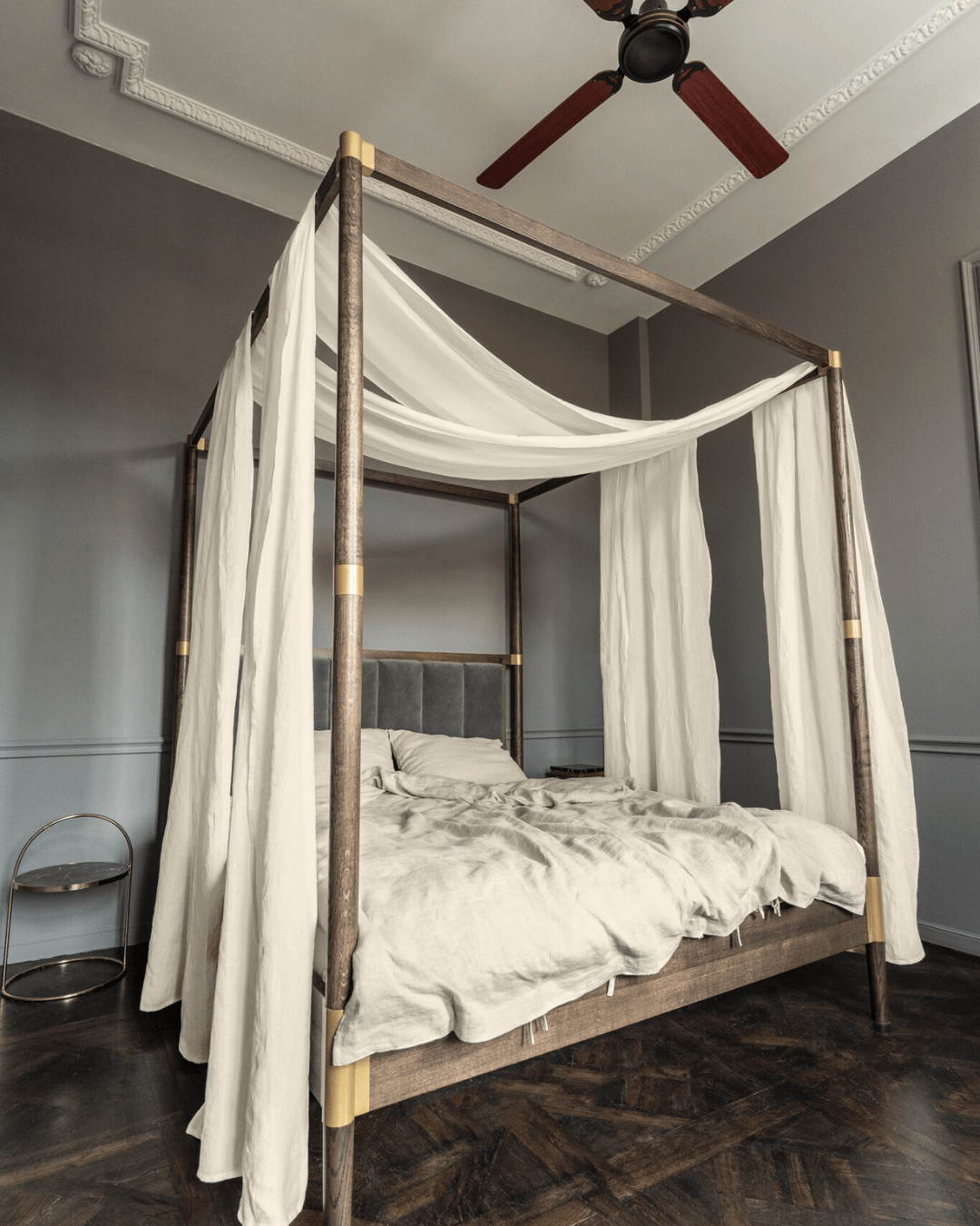 a four poster bed with white drapes and a ceiling fan
