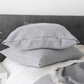 a bed topped with pillows and blankets next to a night stand