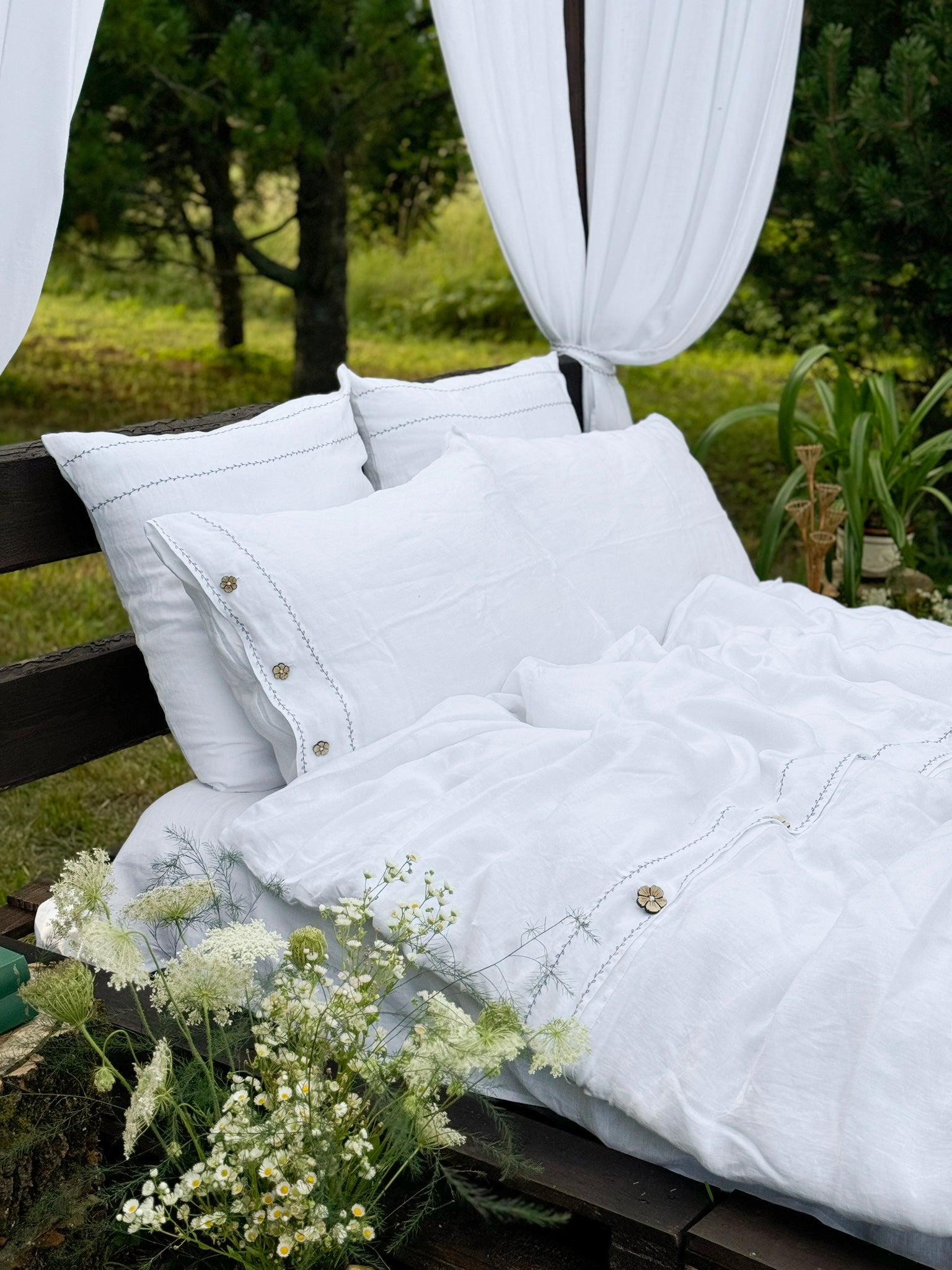 a bed with white sheets and pillows in a field