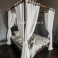 A bedroom with White color canopy bed drapes with ties in boho style. Made by DustyLinen