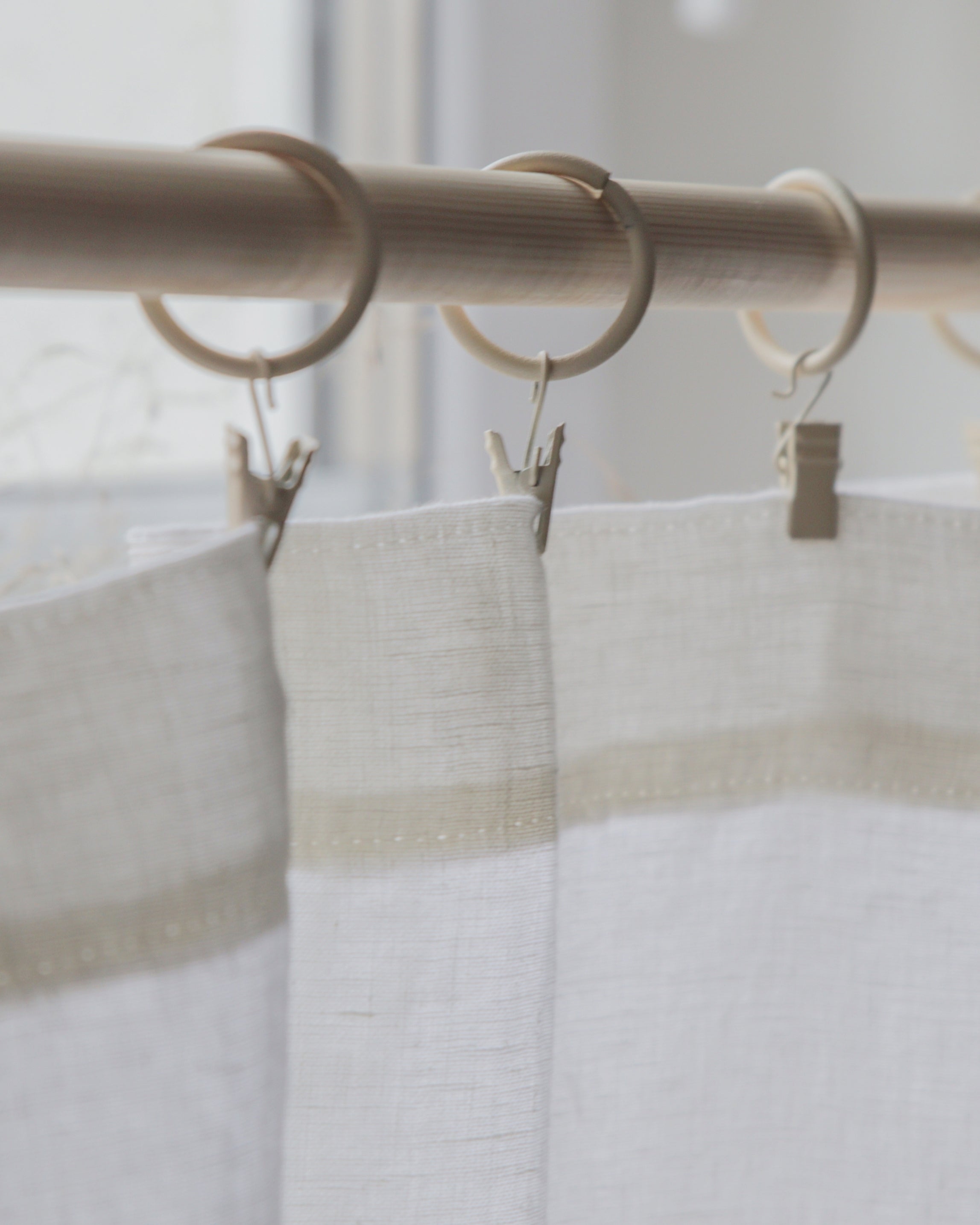 White semi sheer curtains with beige stripes and clips on a rod