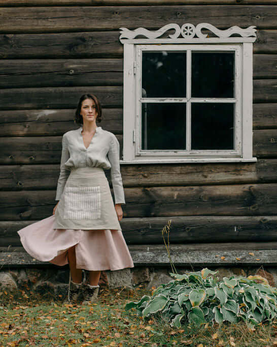 Woman wearing linen half apron near window