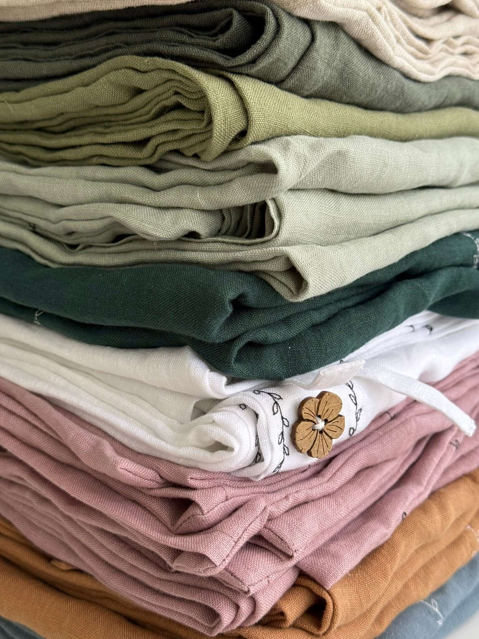 Stacked folded linen fabrics in mixed colors, artisan workshop