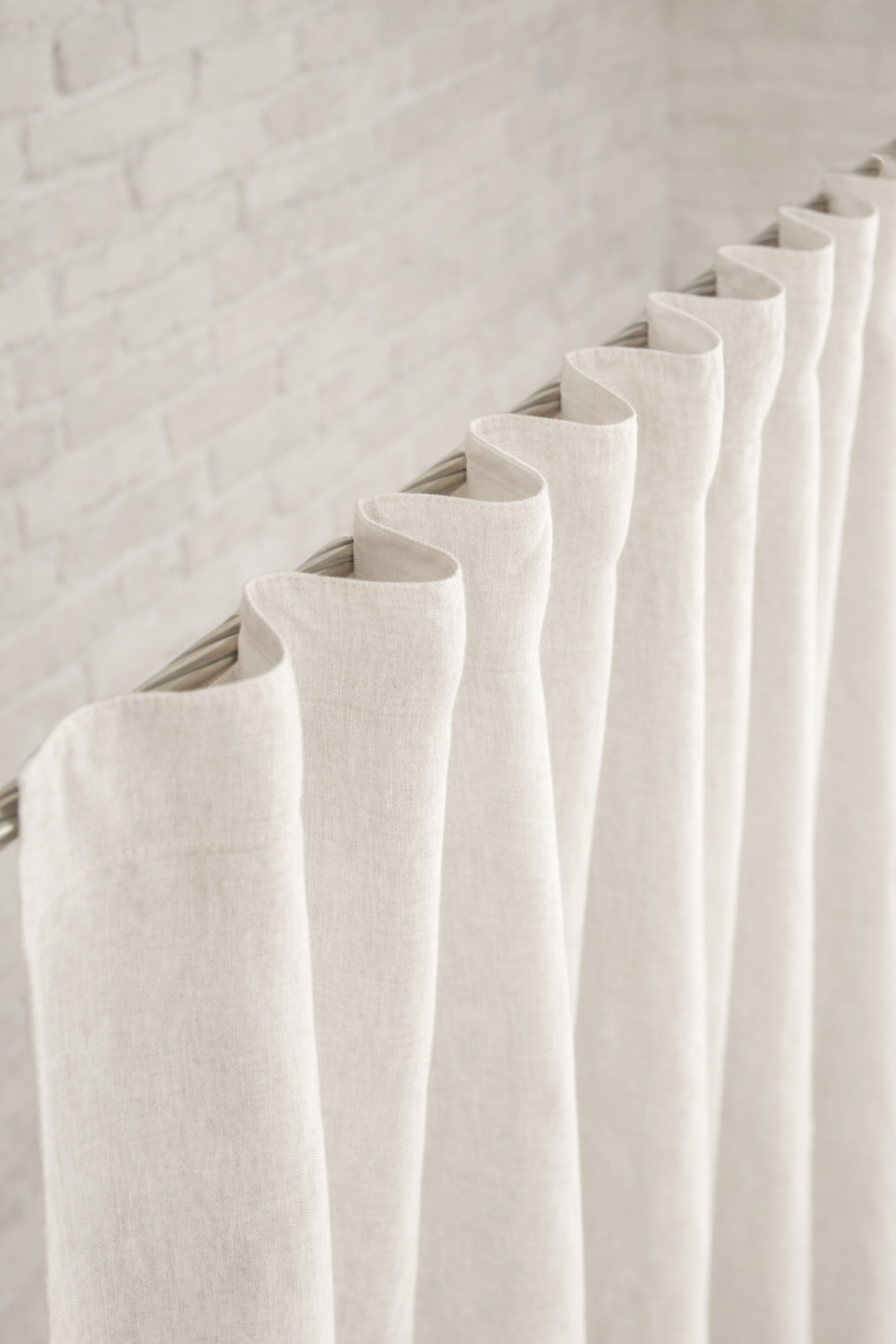 White linen curtainswith tape  hanging against a light gray wall 
