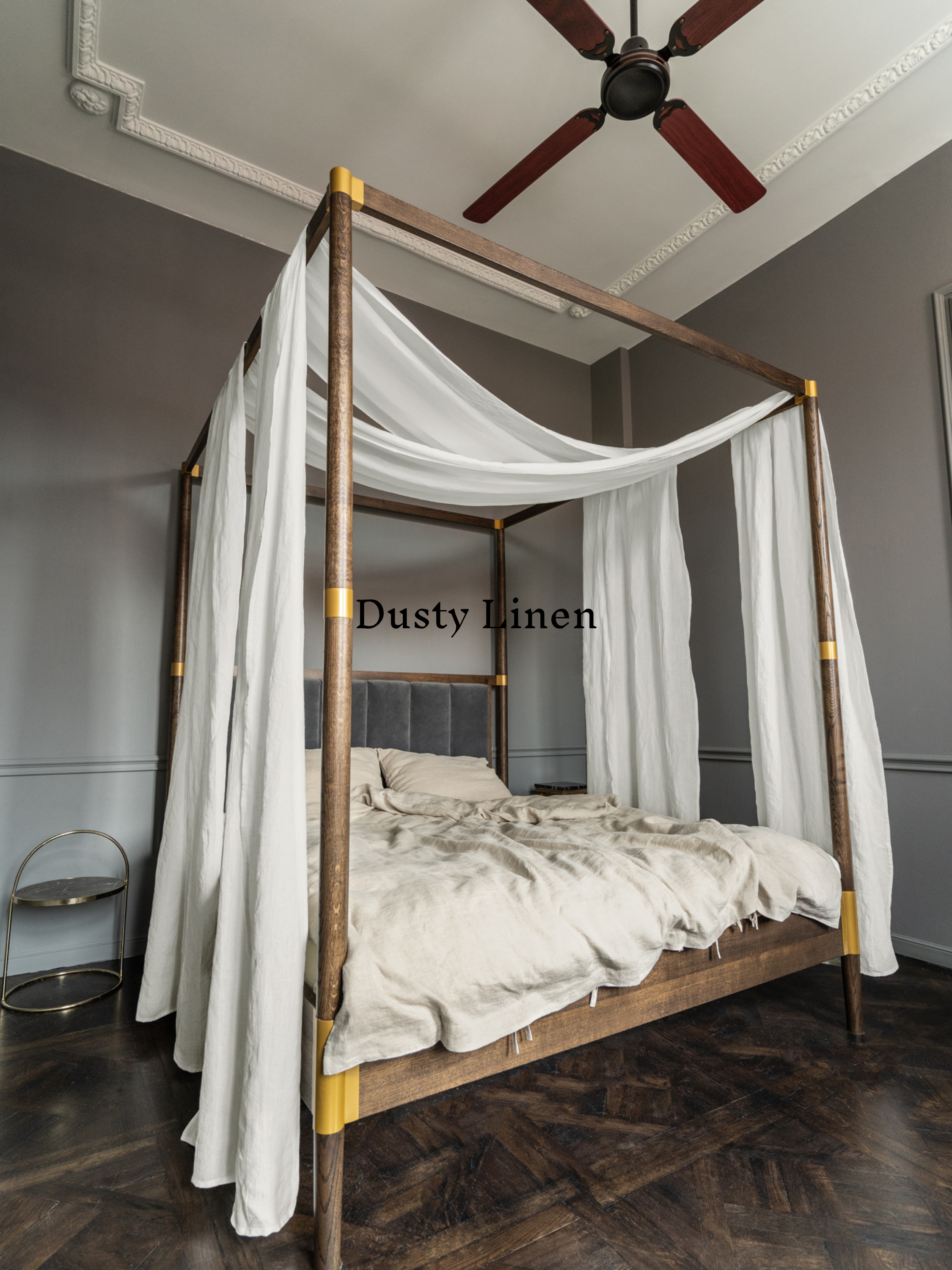 a four poster bed with white drapes and a ceiling fan