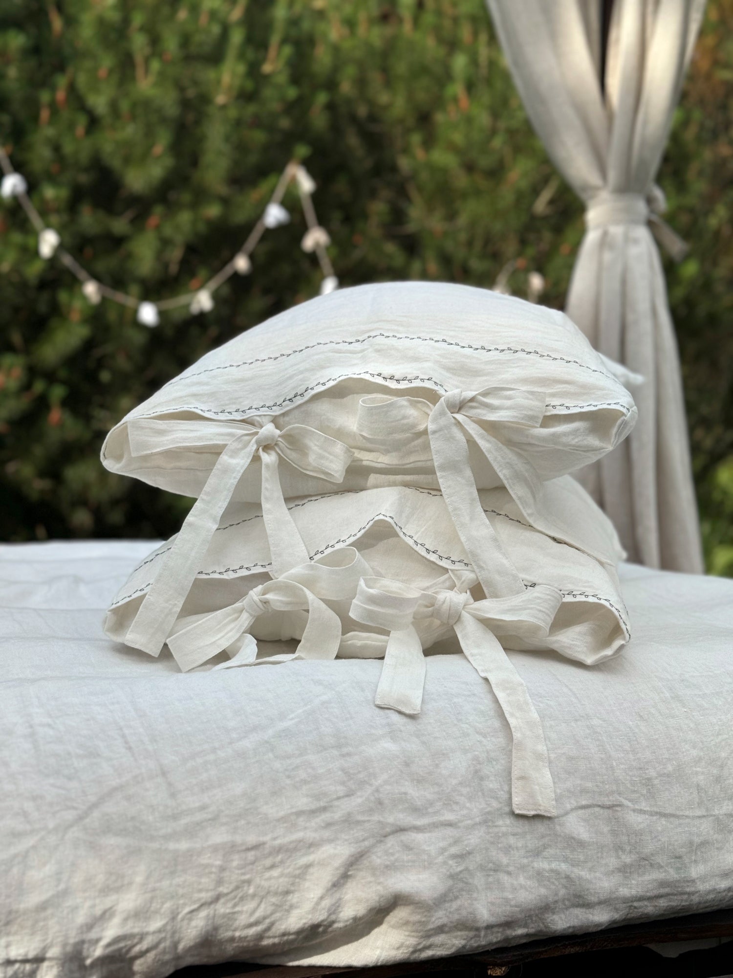 Black embroidered linen pillowcase styled on white bedding in minimalist bedroom