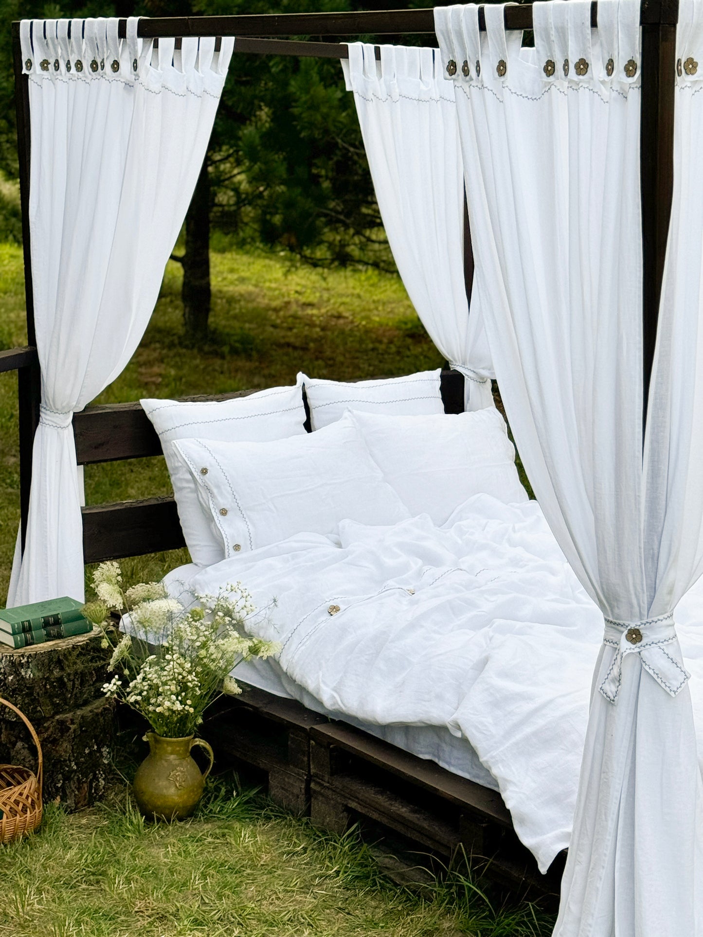 a bed with white sheets and curtains in a field