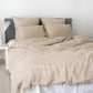 a bed with a beige comforter and pillows