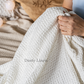 a woman holding a white blanket on top of a bed