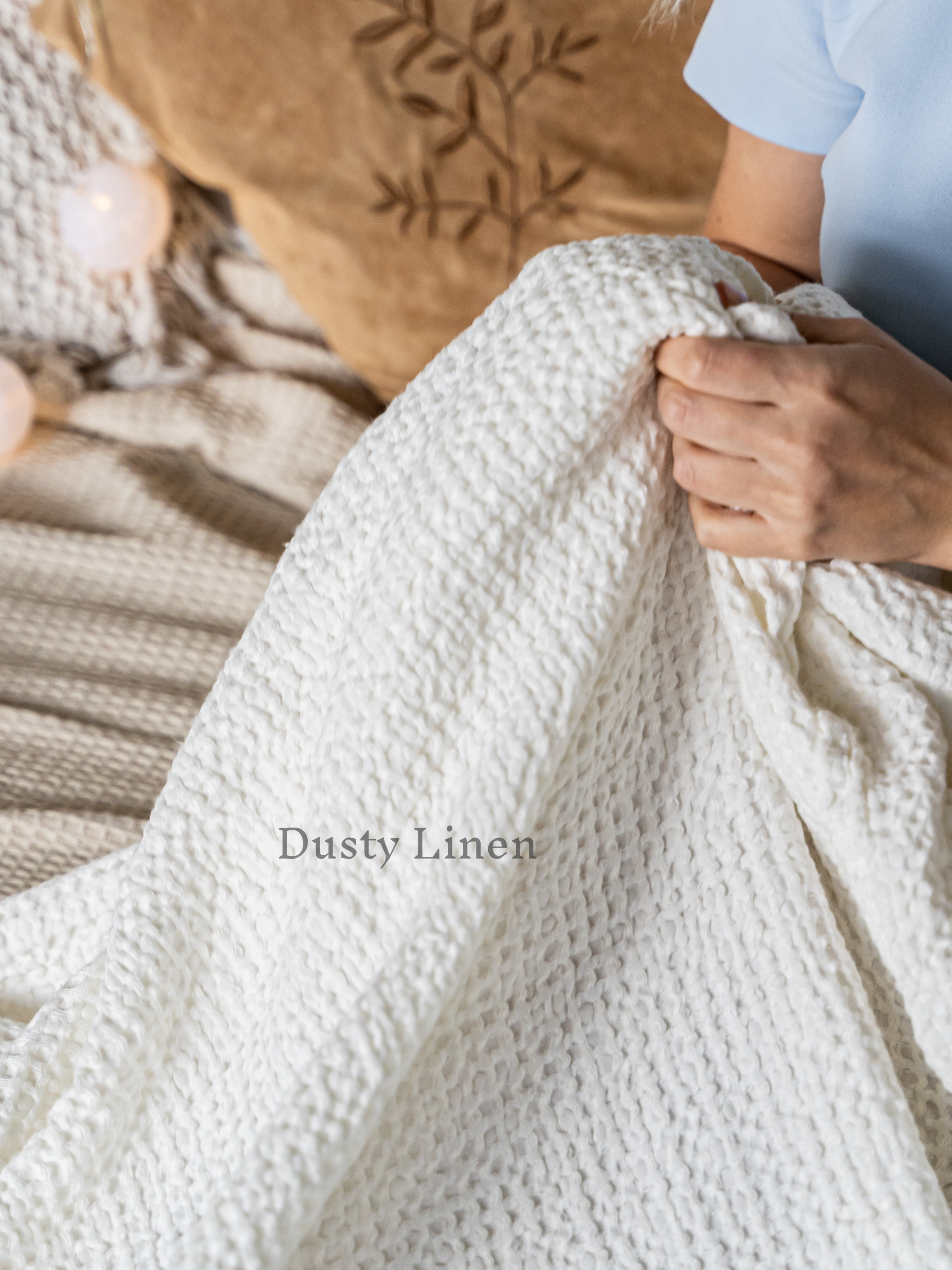 a woman holding a white blanket on top of a bed