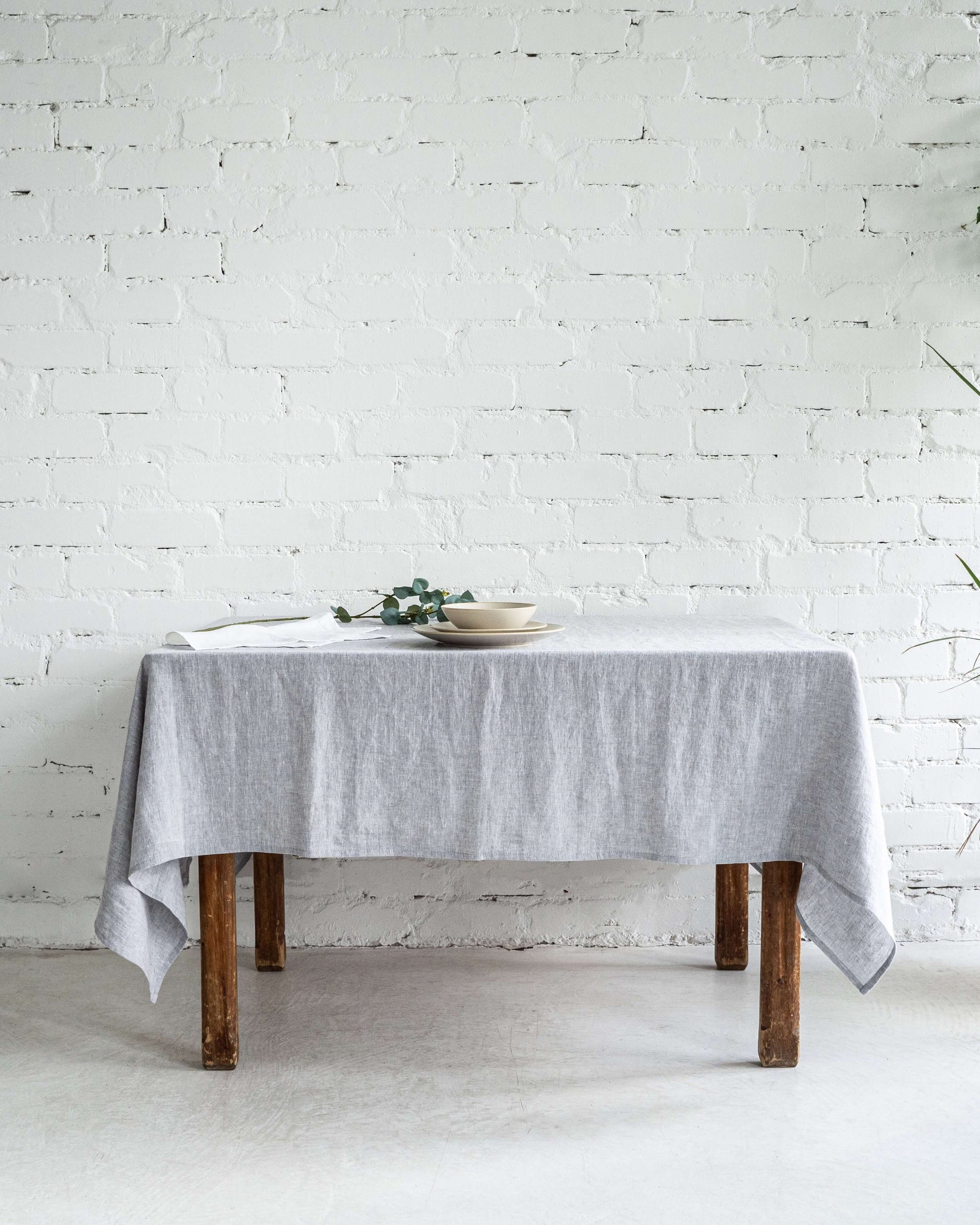 Linen tablecloth in neutral tone, styled dining table top view