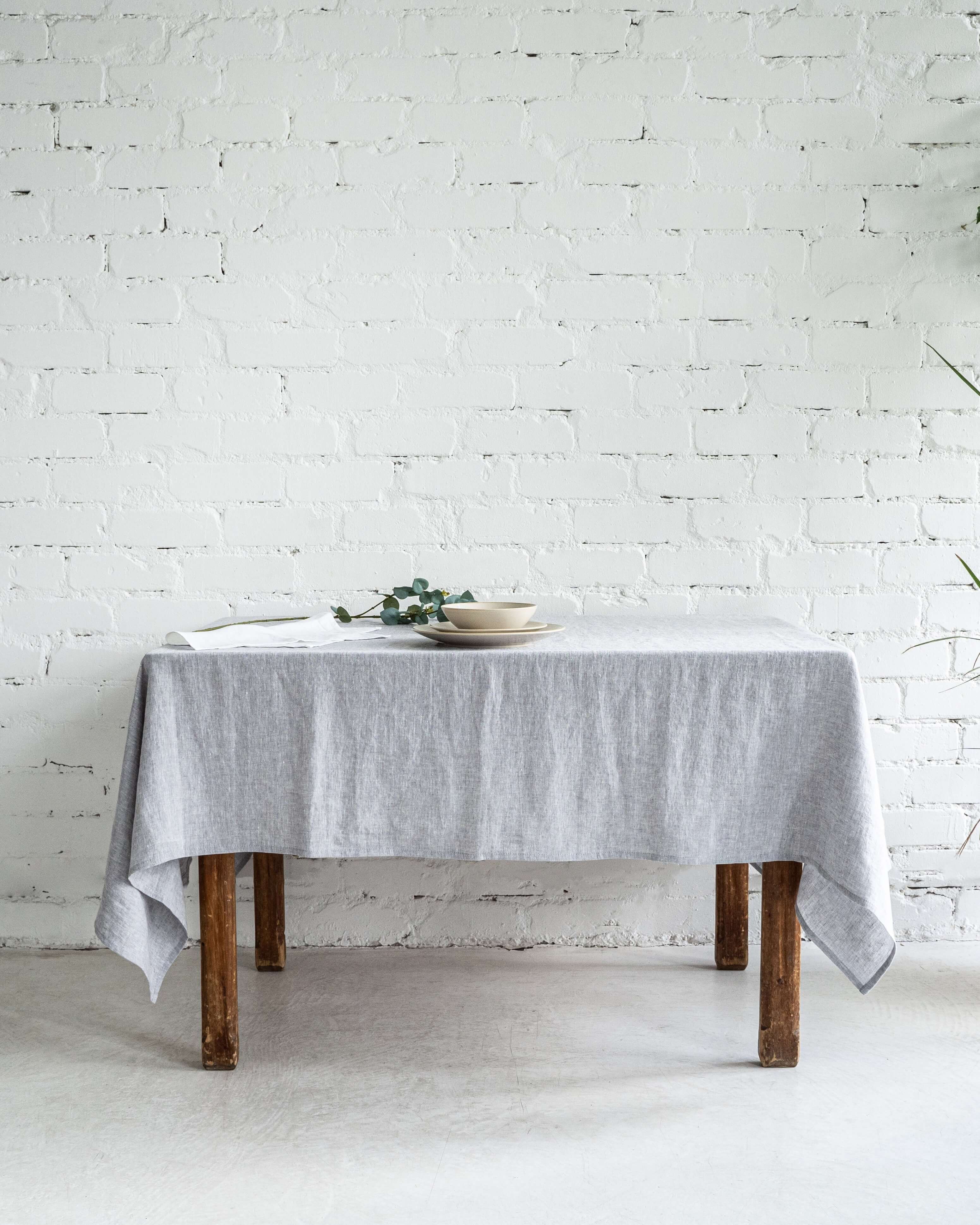 Linen tablecloth in neutral tone, styled dining table top view