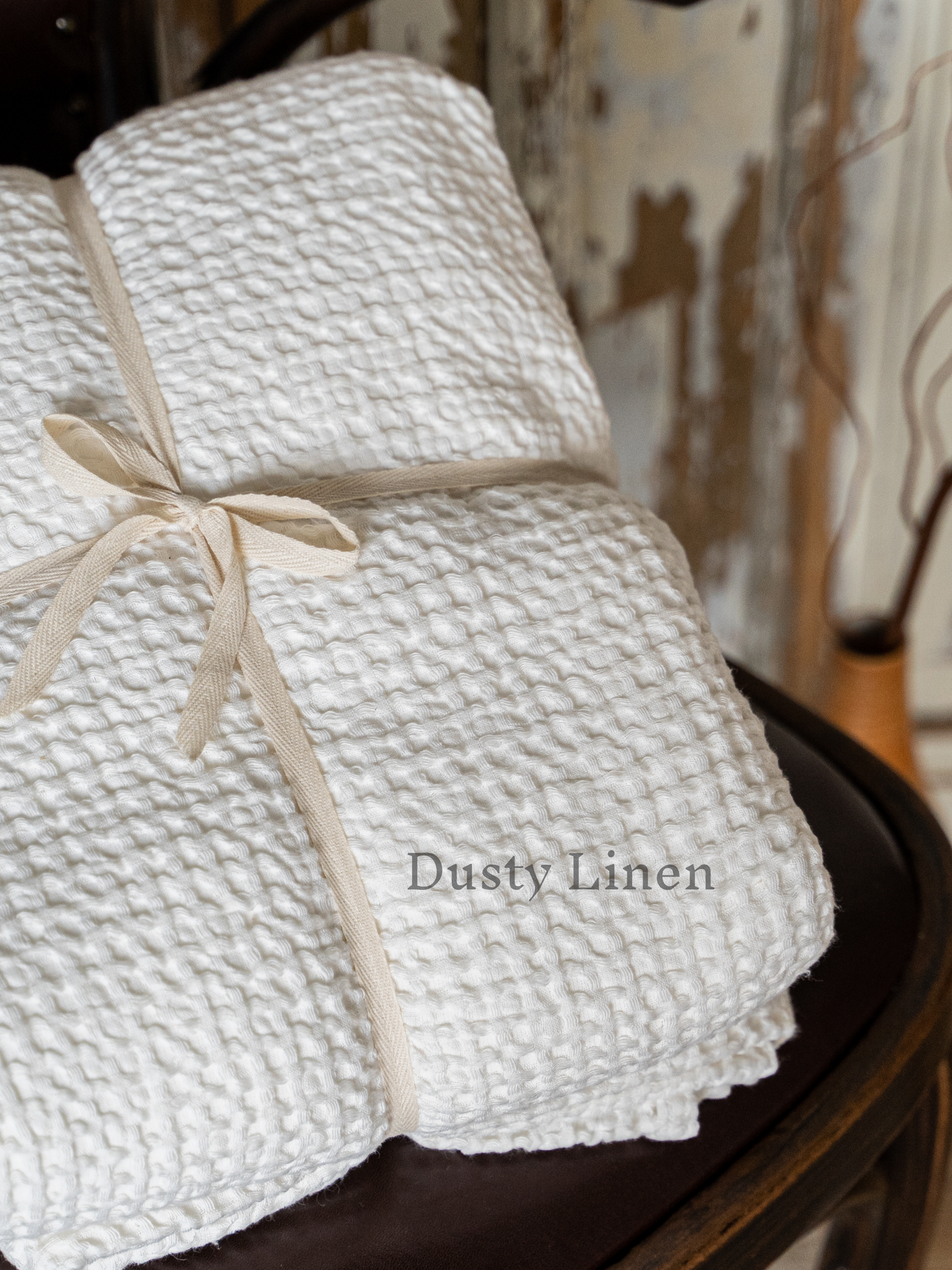 a stack of white blankets tied up on a chair