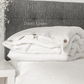 a bed with a white comforter and pillows