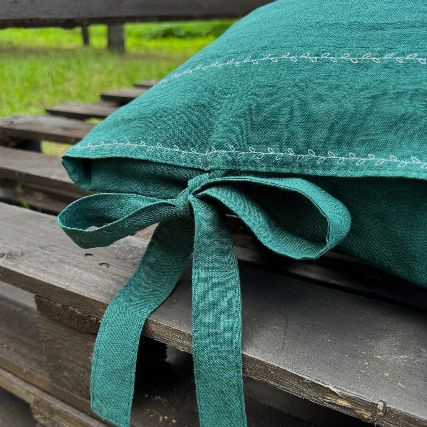 a green pillow tied to a wooden bench