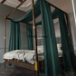 a canopy bed with a green drapes on top of it