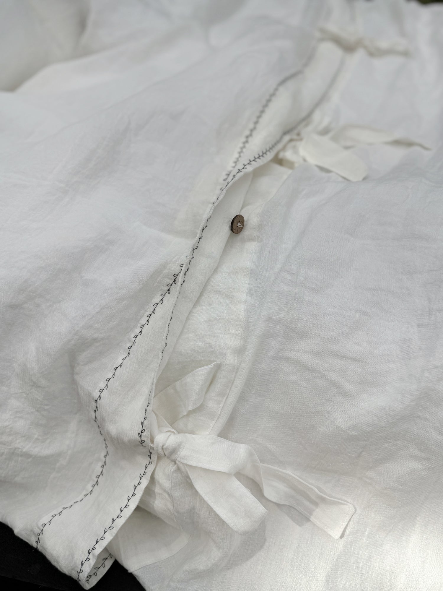 Black embroidered linen duvet cover fabric close-up, softened linen texture