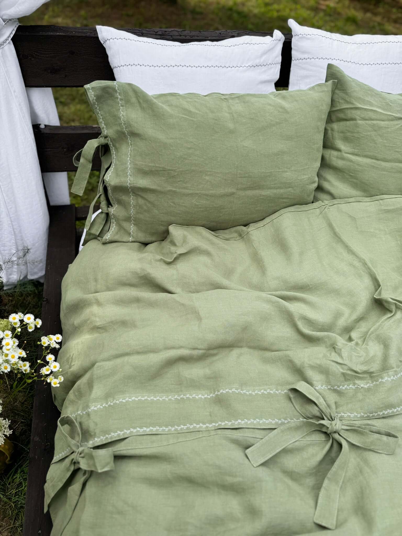 White embroidered linen duvet cover styled on bed, top closure detail